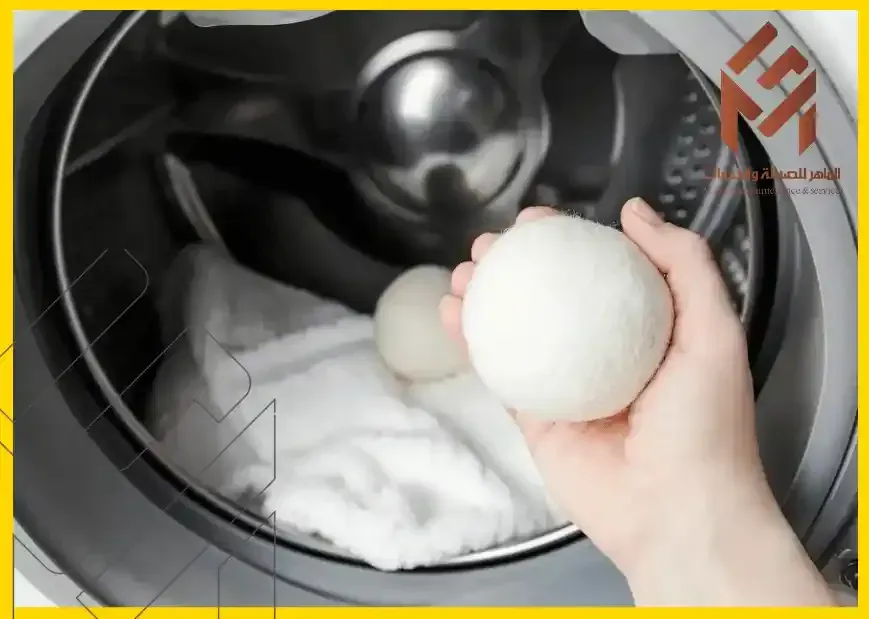 شخص يحمل كرة من القماش الأبيض في الغسالة - ما هي كرة التجفيف وكيف تعمل؟